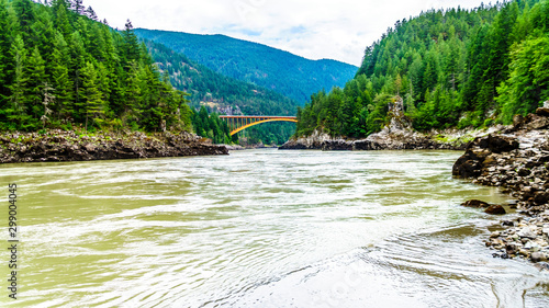 The mighty Fraser River, with the the arch shaped steel structure of the Alexandra Bridge on the Trans Canada Highway in the distance. Viewed from the upstream historic Second Alexandra Bridge photo