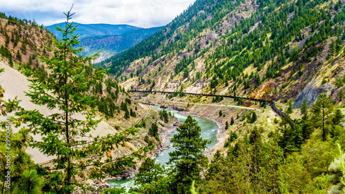 Freight train on the railroad tracks running along the mighty Fraser River flowing in the Fraser Canyon in British Columbia, Canada