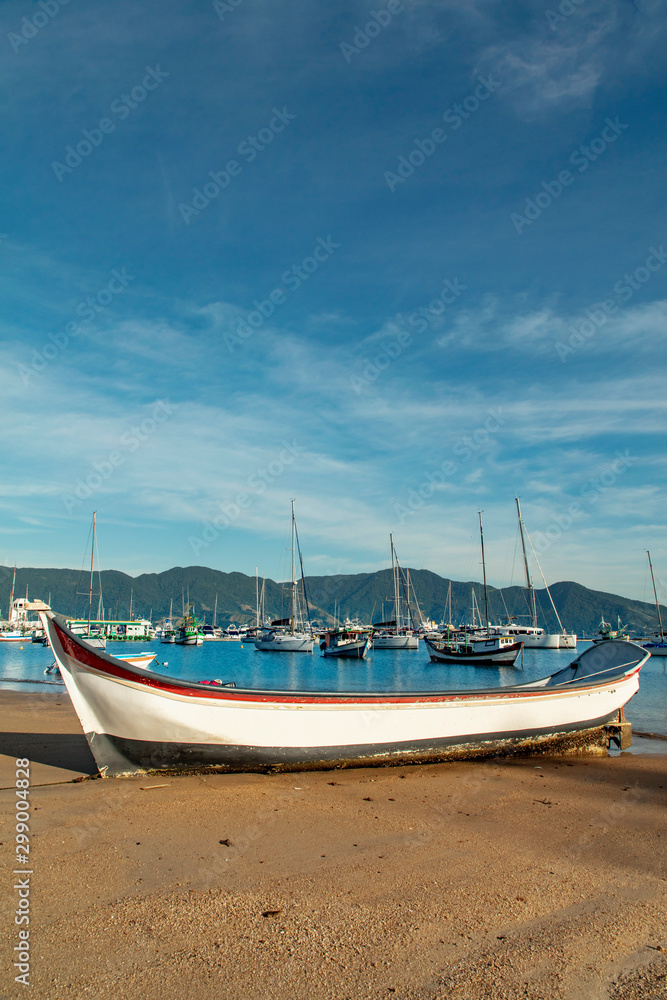 Boats in a bay on the coast of Sao Paulo on a beach in Ilhabela island with blue sea and clear sand in Brazil