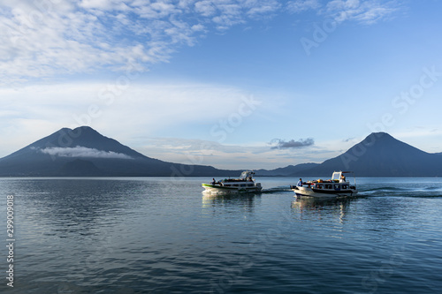 Dos barcos de pasajeros navegan en el Lago de Atitlán Guatemala y en el fondo se ven sus volcanes.