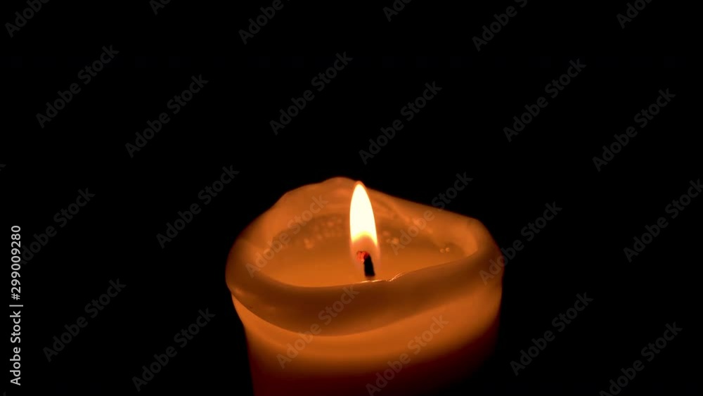 Close-up on one lit candle, orange flame on black background Close-up on one lit candle, orange flame on black background