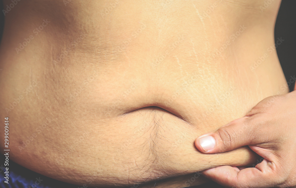 hand touching stomach with belly fat on skin hand touching stomach with belly fat on skin