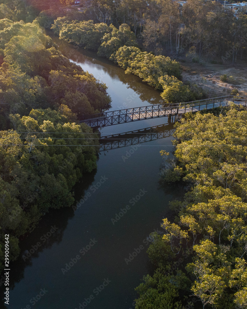 Aerial view of a small bridge above a river and around wetlands.