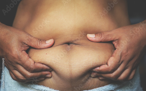 hand touching stomach with belly fat on skin 