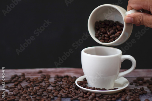 White coffee mugs on a wooden table with coffee beans on the floor.