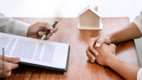 Businessman signs contract behind home architectural model Discussion with a real estate agent rental company staff  at the office property appraisal and valuation concept.