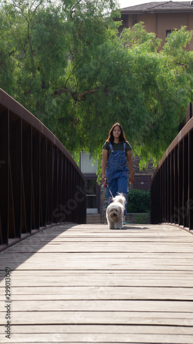teenager walking her white medium dog at the bridge