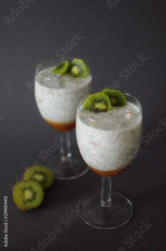 Healthy chia pudding in a glass with fresh kiwi and strawberries jam