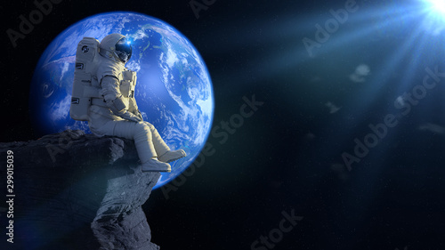 Fototapeta Naklejka Na Ścianę i Meble -  astronaut sitting on a cliff on the Moon in front of planet Earth 