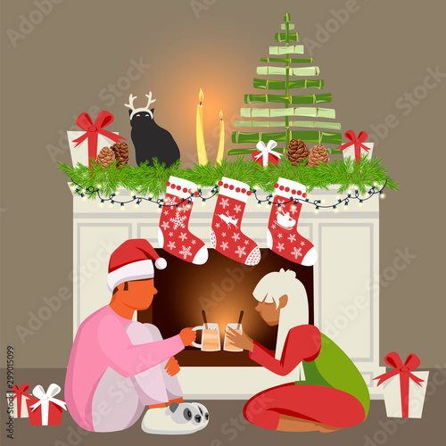 people celebrate Christmas. young couple by the fireplace. guy with a girl drinking eggnog