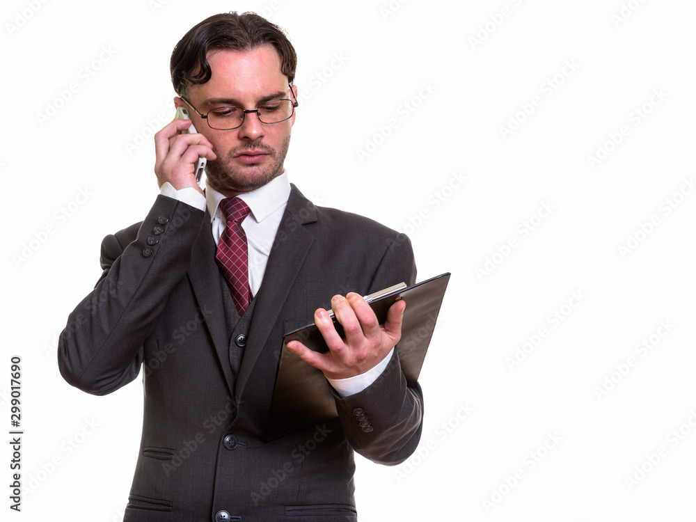Studio shot of young businessman talking on mobile phone while r Studio shot of young businessman talking on mobile phone while r