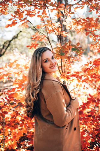 Beautiful smiling woman enjoying autumn in the forest.