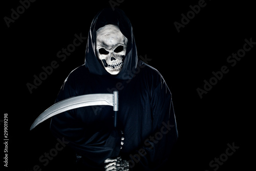 Grim Reaper ghost coming out of the shadows with a scythe or sickle.  The scary demon or monster depicts Halloween and Day of the Dead holiday.