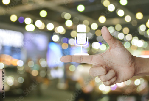 Microphone flat icon on finger over blur light and shadow of shopping mall, Business communication concept