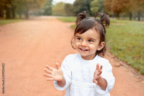 Little happy smilling baby girl clapping hands in the park