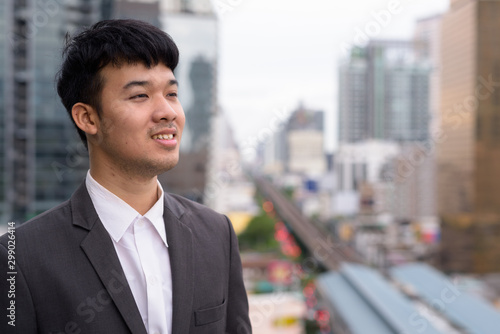 Portrait of young Asian businessman against view of the city