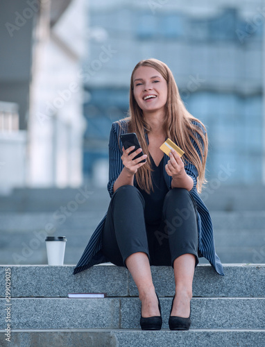 young woman using credit card on city street.