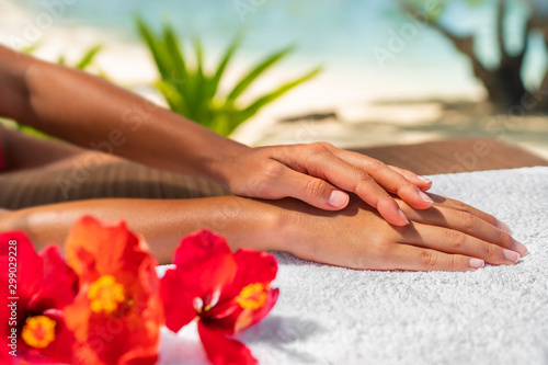 Fototapeta Naklejka Na Ścianę i Meble -  Hand spa massage manicure skin care therapy. Closeup of woman's hands lying on towel with natural hibicus flowers.