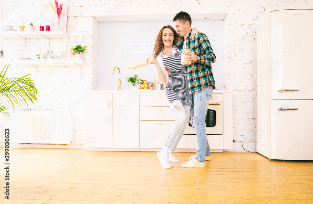 Happy beautiful young couple have fun in the kitchen, dancing, cuddling, cooking food together Happy beautiful young couple have fun in the kitchen, dancing, cuddling, cooking food together
