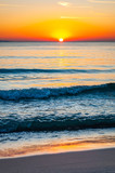 The sunset sun is going down behind the horizon. Tyrrhenian Sea bay with Elba island on the background at the sunset. Cala Violina beach