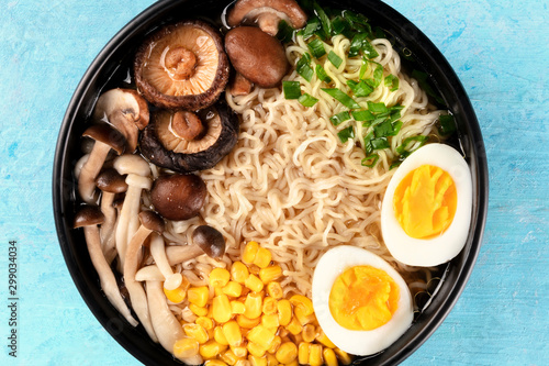 Ramen close-up. Soba with eggs, mushrooms, and vegetables, shot from above on a blue background