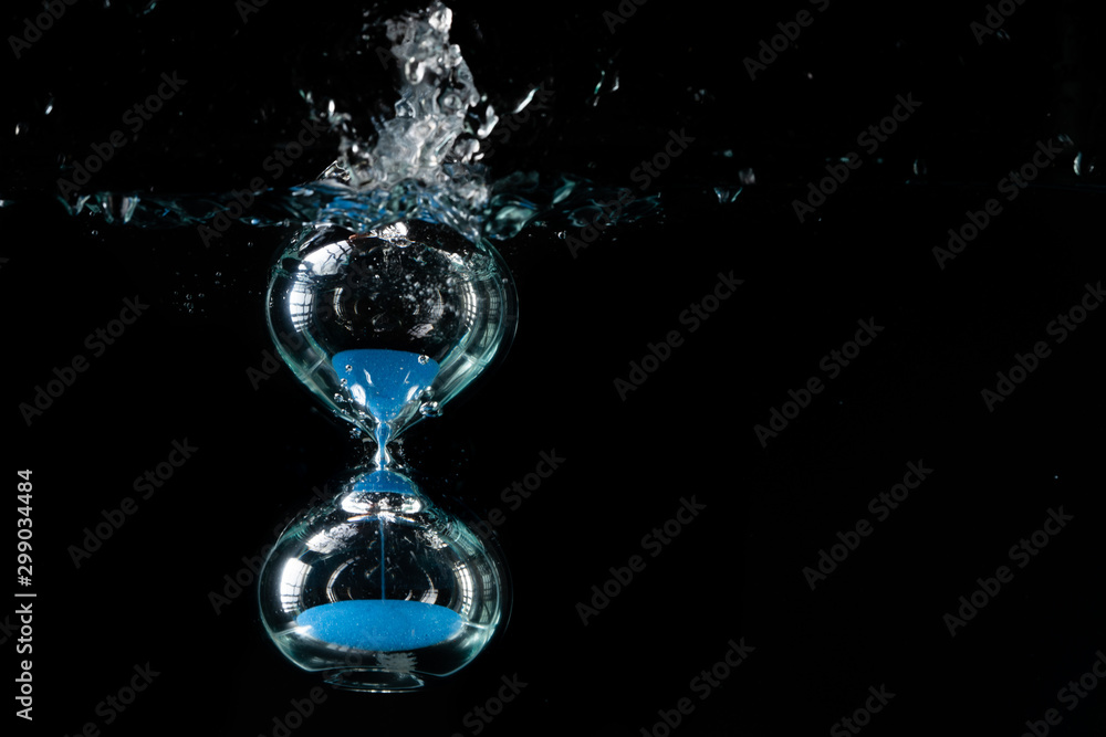 hourglass in water on black background