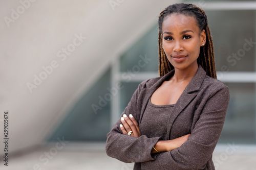 Beautiful female african american business woman CEO in a suit at the workplace, standing confidently with arms folded photo
