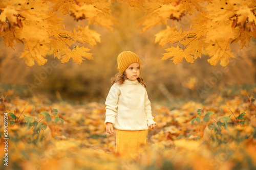 little caucasian girl standing alone in the autumn park and looking away