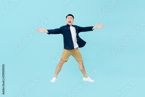 Young dynamic Asian man looking amazed jumping in midair
