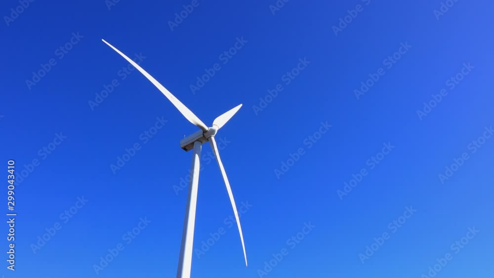 Wind turbine operates against clear, deep blue sky. Wind turbine operates against clear, deep blue sky.