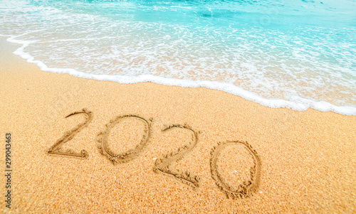 Happy New Year 2020, lettering on the beach with wave and blue sea. Numbers 2020 year on the sea shore, New Years concept.