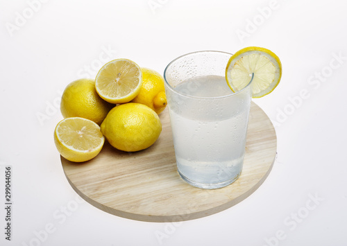 Top view of lemonade glass next to yellow lemons, on wooden board