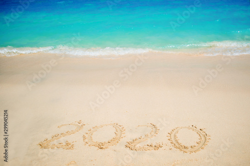 New 2020 year in the South, the sea. Sea surf. Blue wave is coming ashore. Inscription on sand,