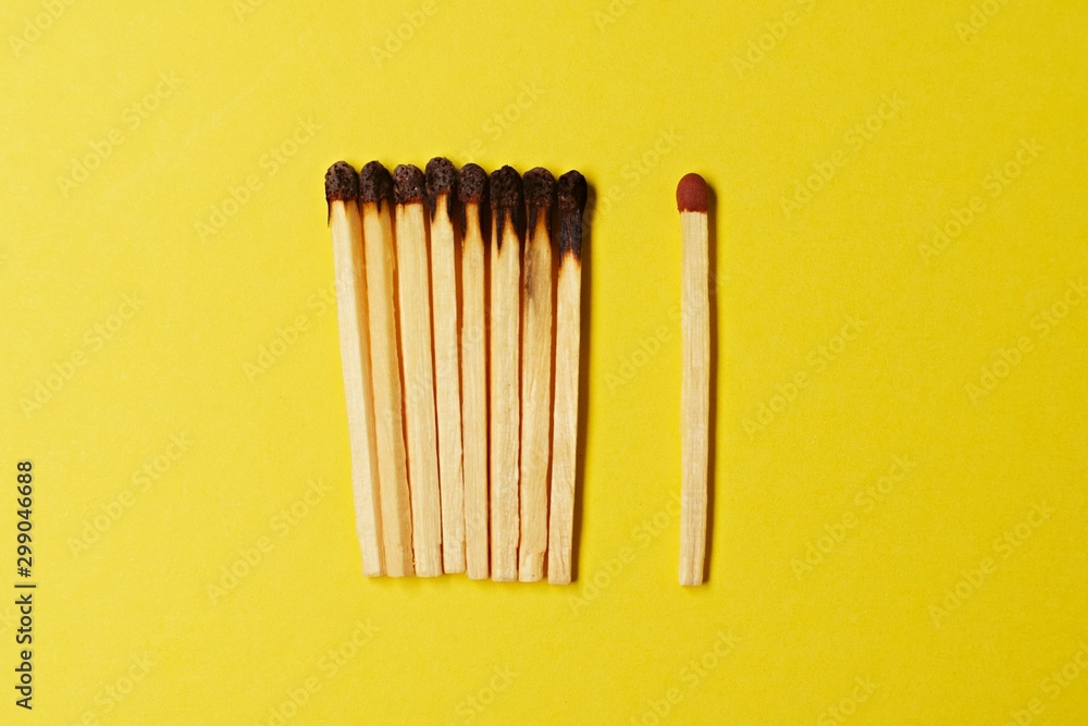 Symbol of danger with matches on yellow background top view , pile of match arrange in a row with one unBurnt match , unlit matches , unique and various concept Symbol of danger with matches on yellow background top view , pile of match arrange in a row with one unBurnt match , unlit matches , unique and various concept