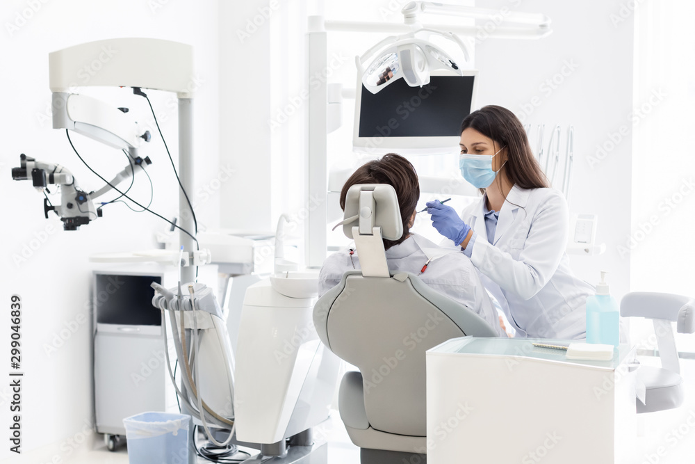 Naklejka premium Pretty dentist doctor treating patient in dental clinic