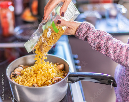 Home cook adding vitali pasta to a saucepan of cooking mushrooms - a stage in making a healthy and nutritious mushroom pasta dinner photo