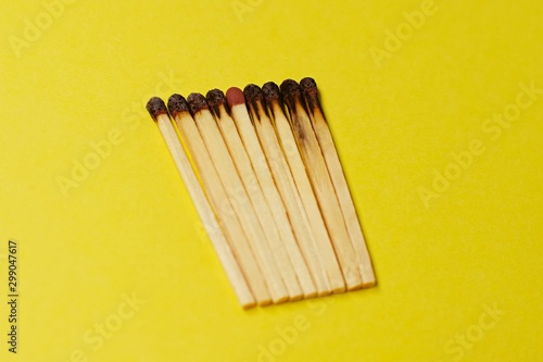 Symbol of danger with matches on yellow  background top view , pile of burnt matches  arrange in a row with one  unBurnt match in the middle  , unlit matches , unique and various concept   