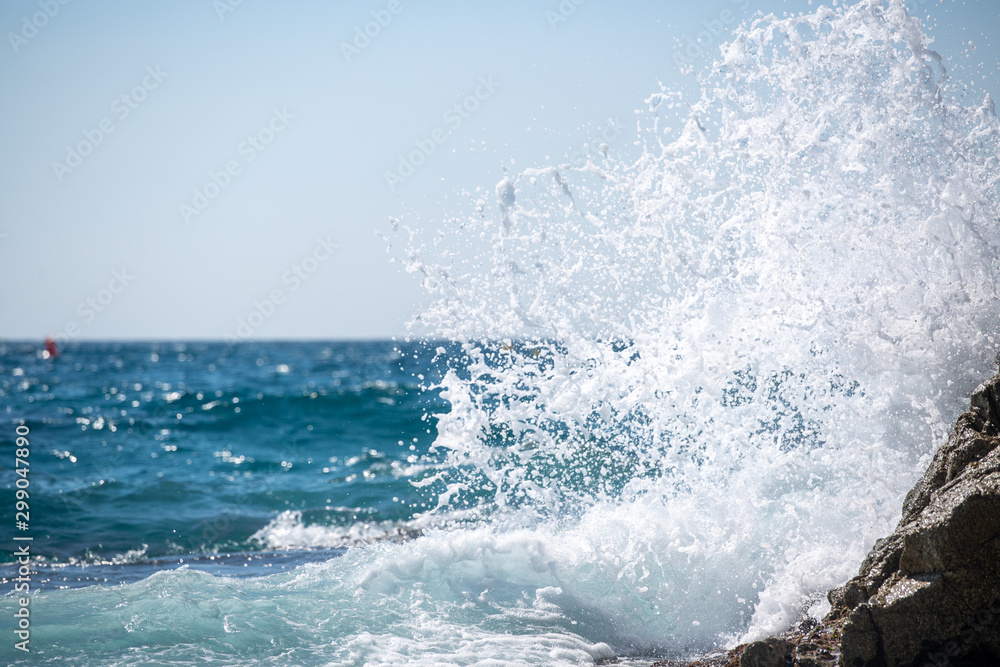 sea wave splashes over stone