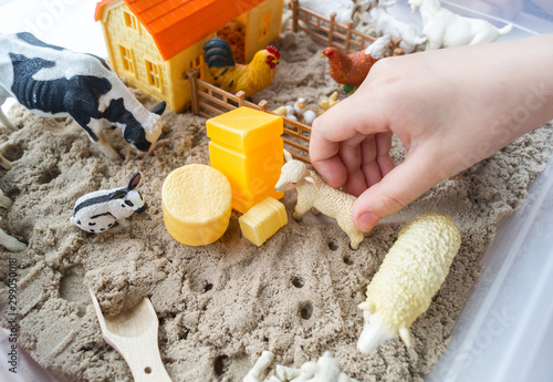 Montessori material. Children's hands play an animal figure. Kinetic sand