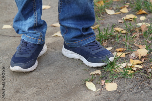  closeup photo baby feet in sneakers and jeans on a forest path