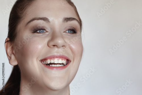 Close up portrait of young brunette woman with blue eyes widely laughing. Natural make up, bottom view.. Indoors, copy space, selective focus.