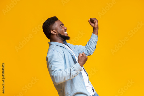 Portrait of excited african guy celebrating success with clenched fists