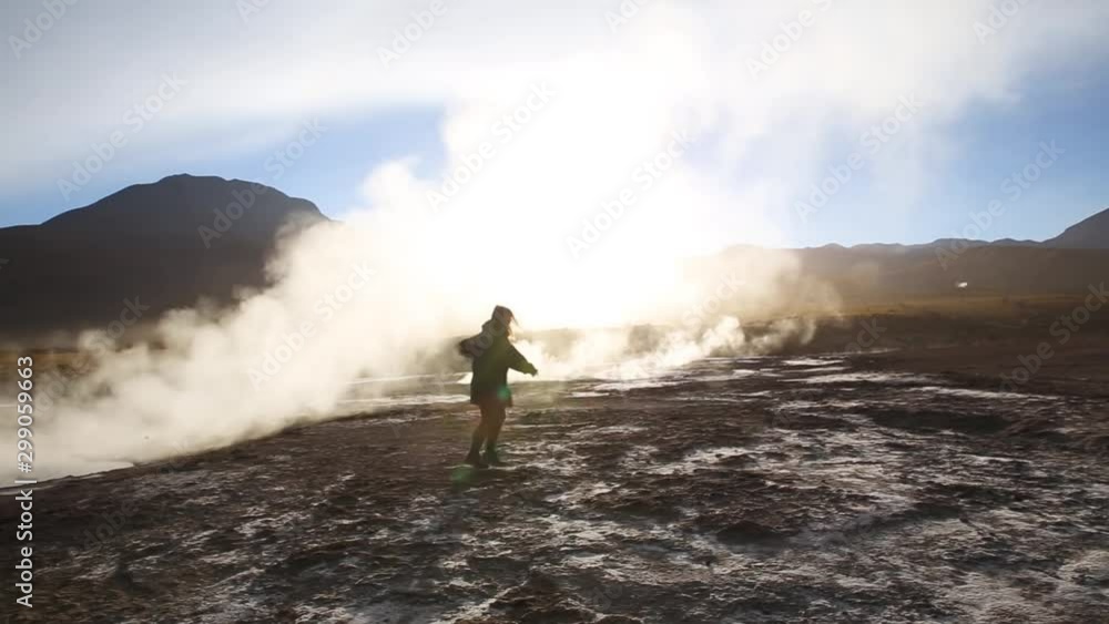 Silhouette of a dancing woman in front of steamy geyser in rocky mountain range at sunrise Silhouette of a dancing woman in front of steamy geyser in rocky mountain range at sunrise