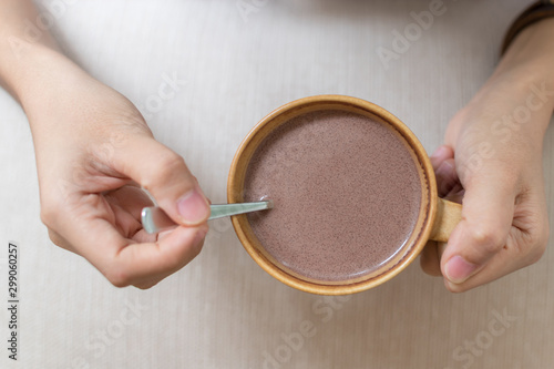 Hand 's woman holding hot chocolate on wooden table background at coffee shop.Holiday concept.