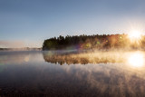A gentle morning on the lake with fog over the water in the sun. USA. Maine