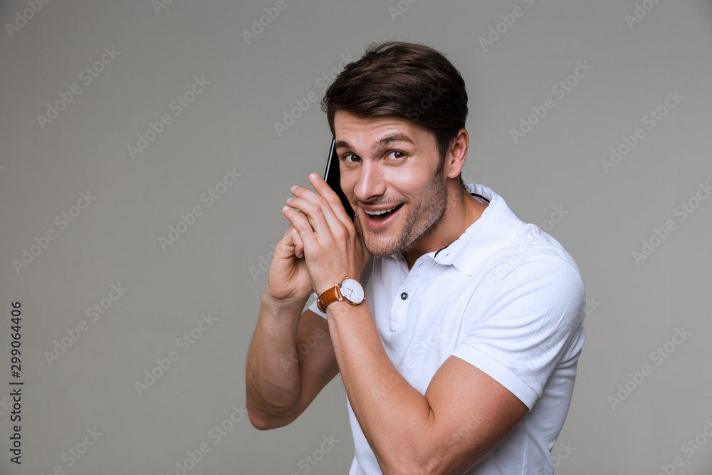 Cheerful handsome young man talking by mobile phone. Cheerful handsome young man talking by mobile phone.