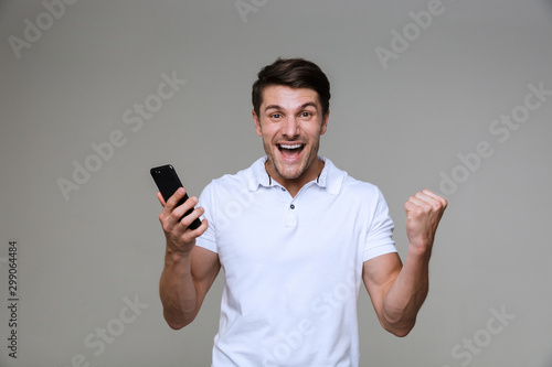 Emotional young man using mobile phone make winner gesture.