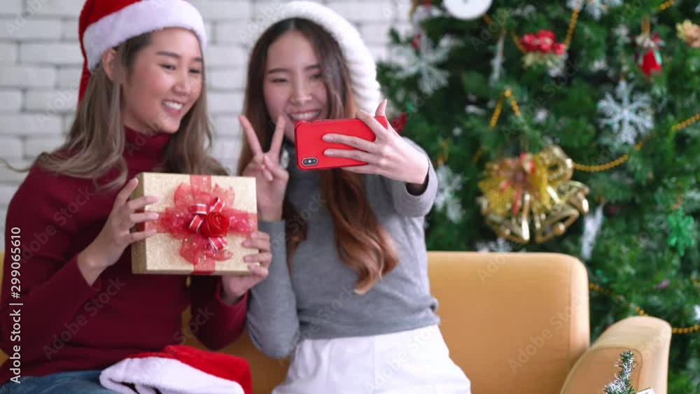 Asian women showing gift and taking a selfie by mobile smartphone in Christmas holiday Asian women showing gift and taking a selfie by mobile smartphone in Christmas holiday