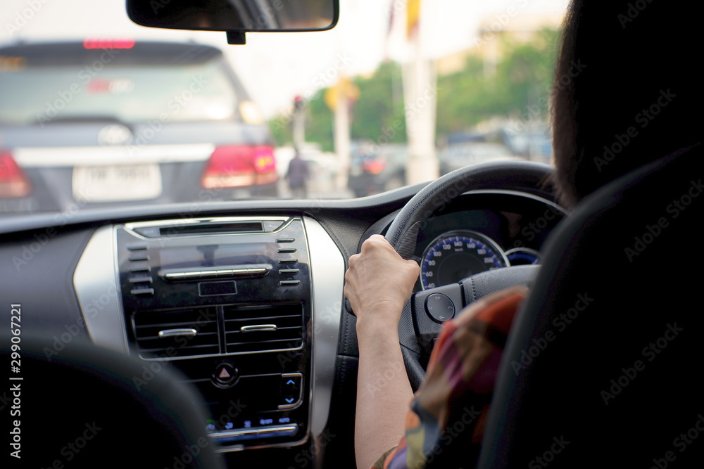 Hands of driver on steering wheel, driving a car concept. Woman in car, Driving on a traffic jam.