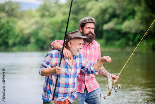 Sunny summer day at river. Rod tackle. Fishing equipment. Hobby sport. Fishing with spinning reel. Fishing peaceful activity. Father and son fishing. Grandpa and mature man friends. Fisherman family